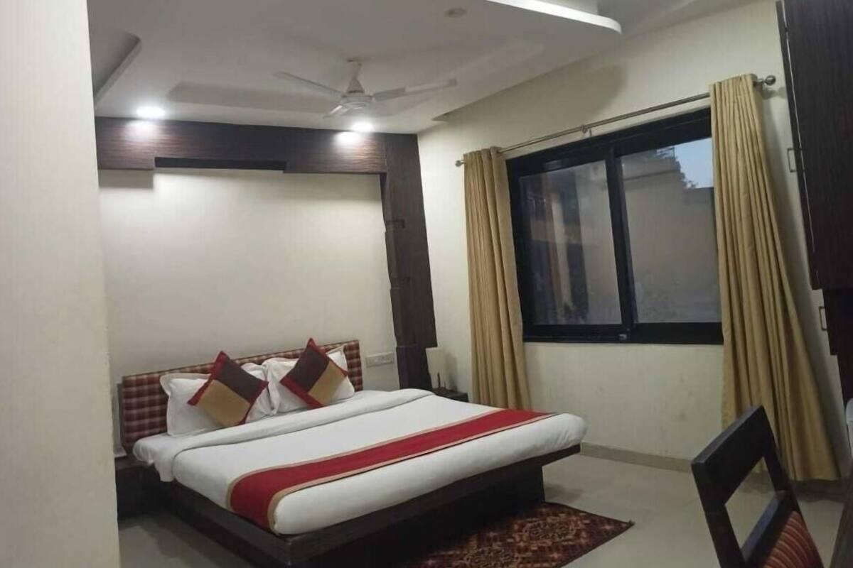 A bedroom with a bed, a ceiling fan, a window with curtains, and a nightstand.