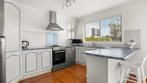 A modern kitchen with white cabinets, a stainless steel range, and a large island with bar stools.