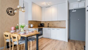 A modern kitchen with white cabinets, a wooden countertop, and a dining area with a table set for two. - Sun & Snow Perłowa Przystań (Kolobrzeg)