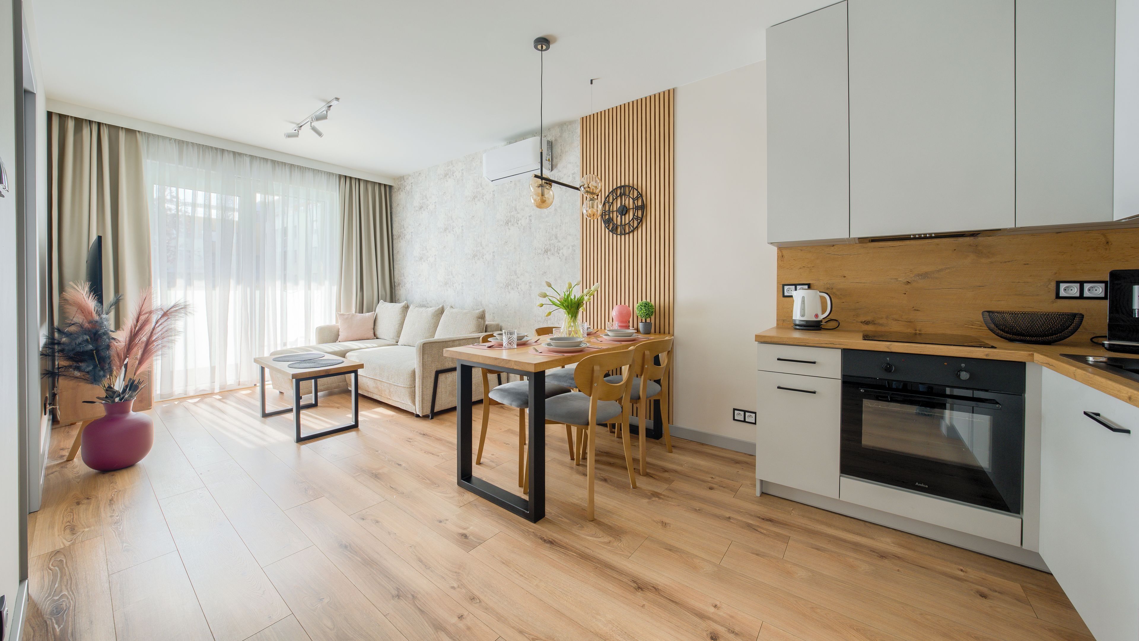 A modern kitchen with wooden cabinets, a built-in oven, and a dining area with a wooden table and chairs.