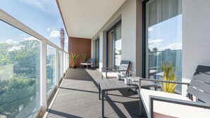 A balcony with a view of trees and a building. There are two chairs and a small table with a vase. - Apartamenty Sun & Snow Perłowa Przystań Kołobrzeg (Kolobrzeg)