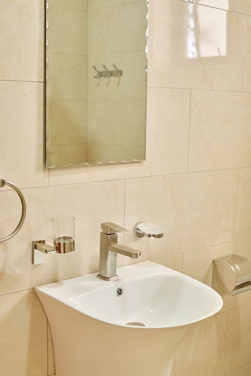 A bathroom with a white sink, a mirror, and a towel dispenser.