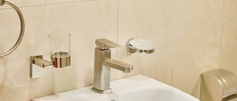A bathroom with a white sink, a mirror, and a towel dispenser.