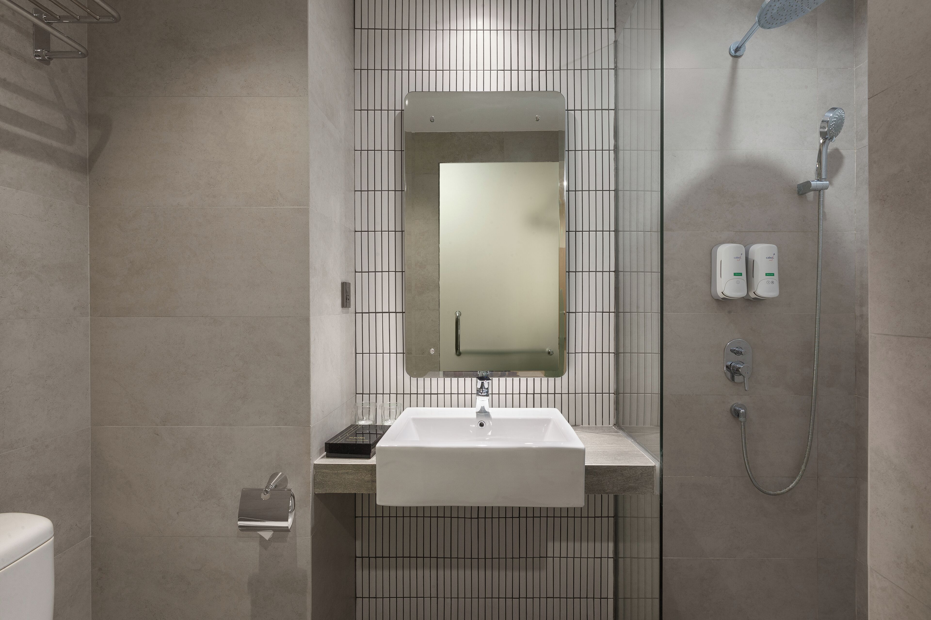 Un baño con lavamanos blanco, espejo y ducha.