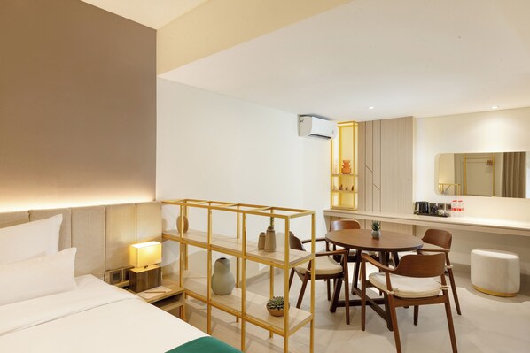 A hotel room with a bed, bedside table, lamp, wooden chair, dining table, chairs, and a small stool. - Elsotel Purwokerto by Daphna Management (Purwokerto)