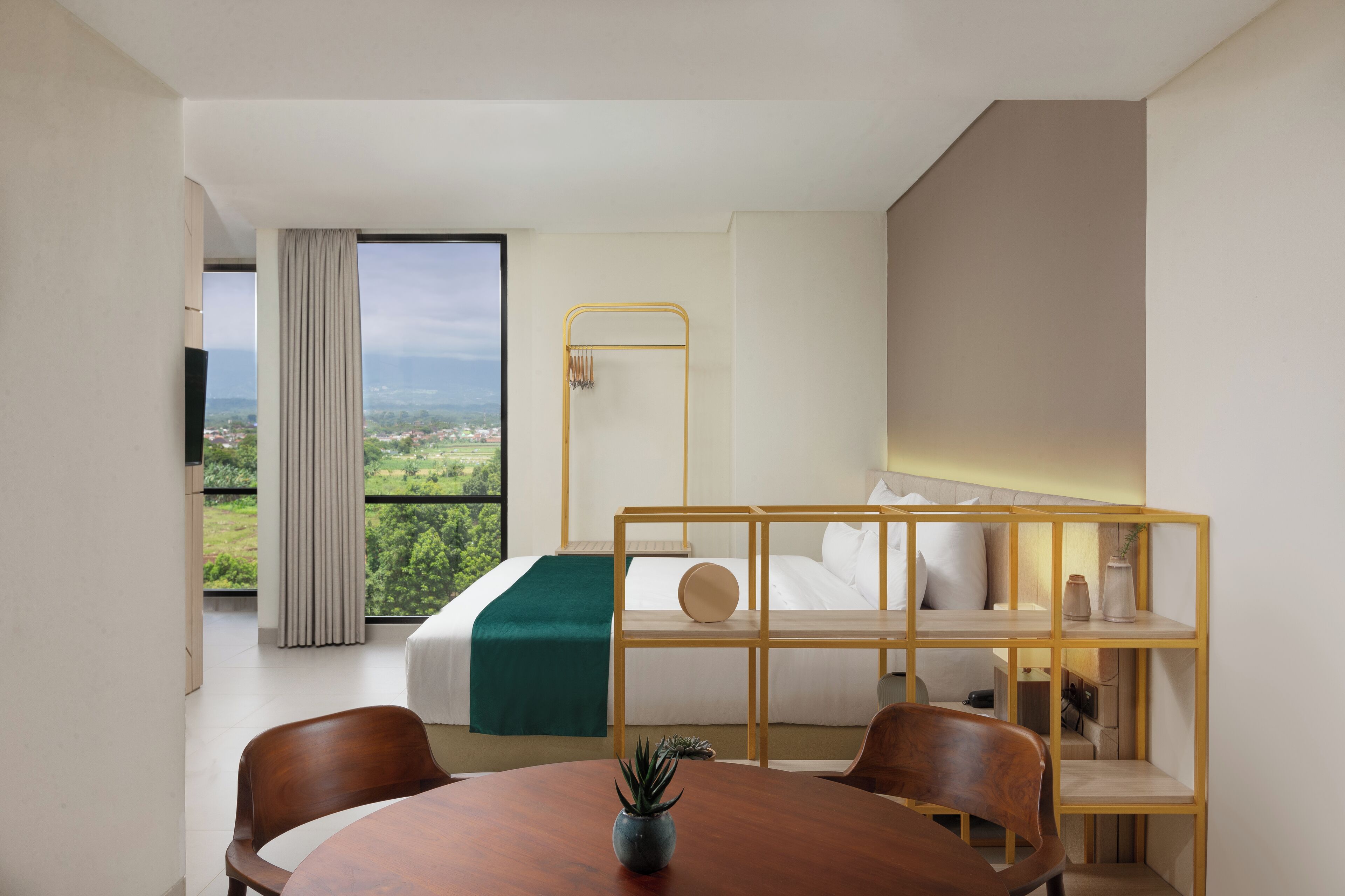 Habitación de hotel con cama, literas, una mesa de comedor con sillas, una planta en maceta y vistas al exterior.