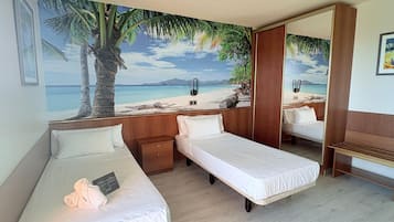 Habitación de hotel con dos camas individuales, una mesita de noche de madera, una pequeña mesa y un mural grande con motivos playeros en la pared.
