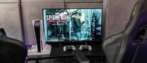 A gaming setup with a large TV, two gaming chairs, and a console.