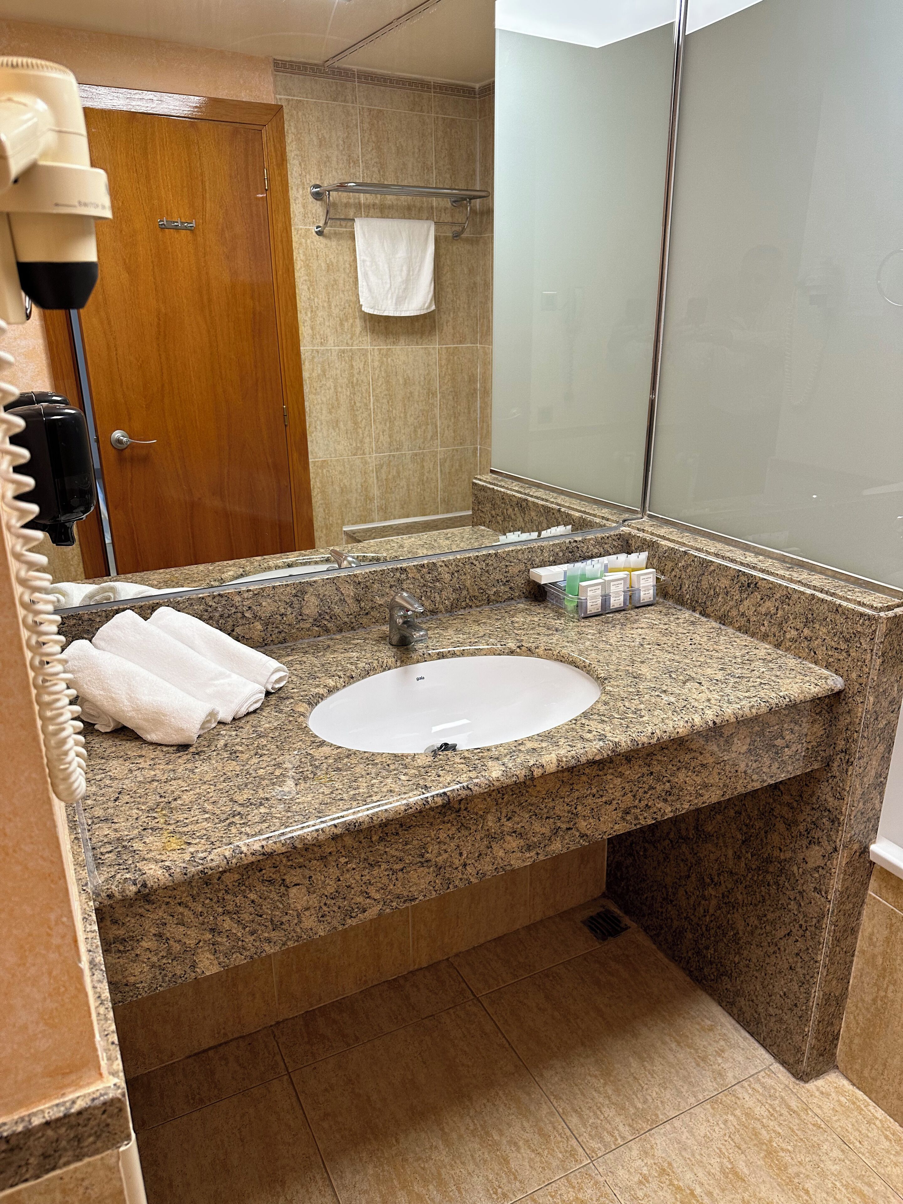 A bathroom with a granite countertop, a sink, a mirror, and a towel rack.