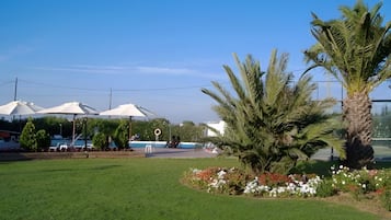 Een gazon met palmbomen en witte parasols.