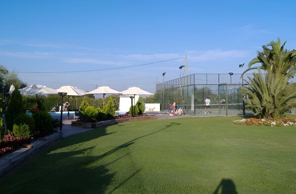 A well-maintained outdoor area with artificial grass, a tennis court, and a seating area with umbrellas. - Cambrils Paradise Resort (Vinyols i els Arcs)