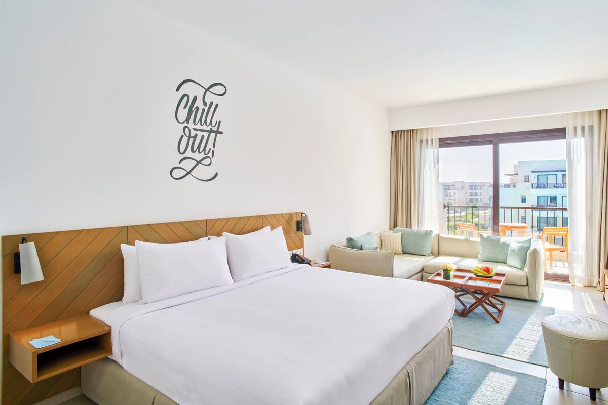 Une chambre d’hôtel avec un grand lit, un canapé, une table basse et une vue sur la ville.