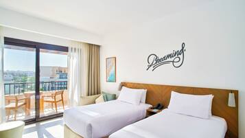 A hotel room with two beds, a balcony, and a city view.