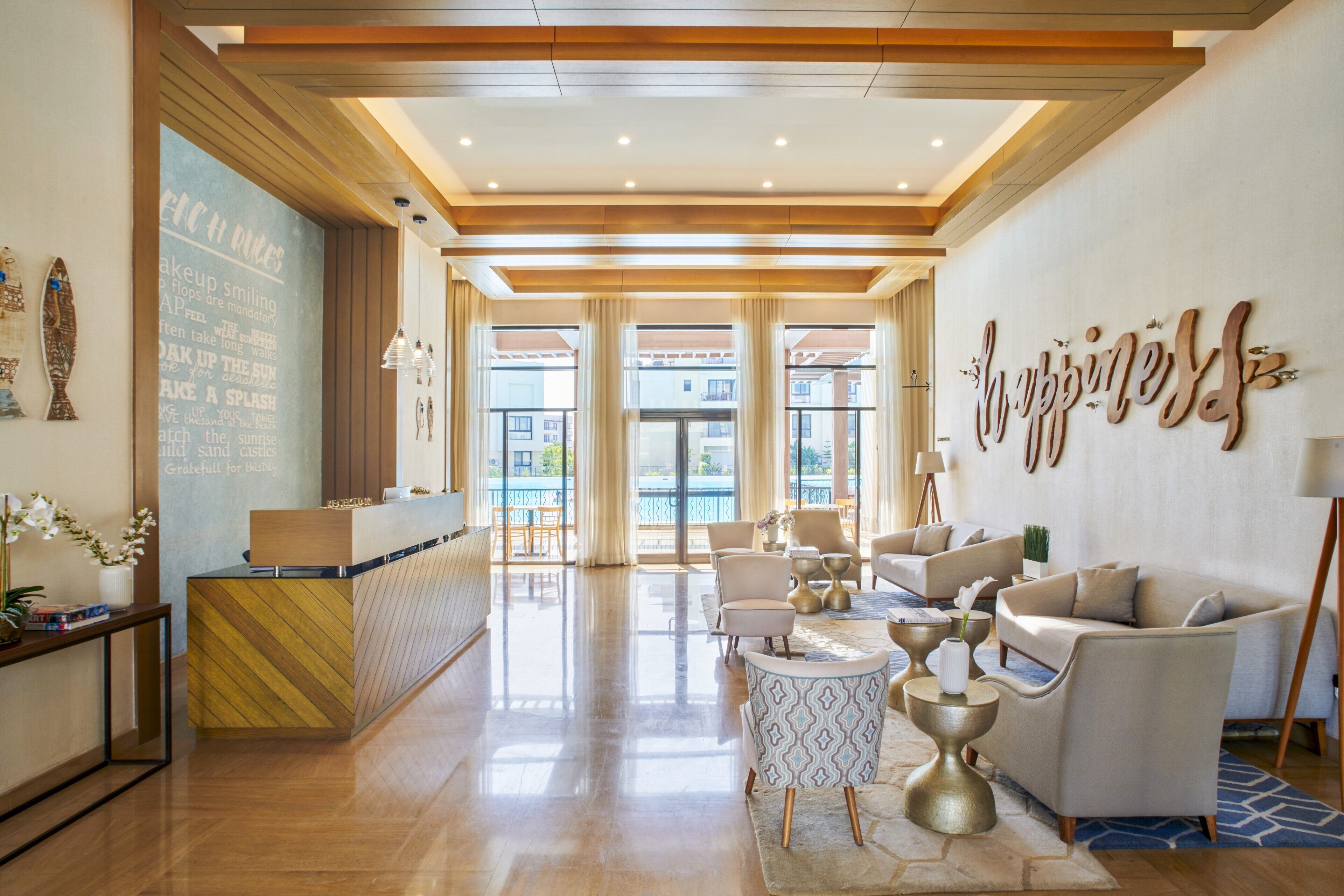 A hotel lobby with a reception desk, seating area, and large windows.