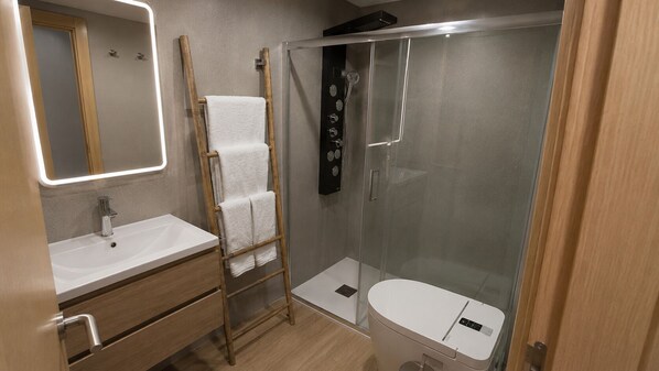 A modern bathroom with a sink, mirror, towel rack, and glass-enclosed shower. - Casa Violeta by Blossom Hotels. (Granada)