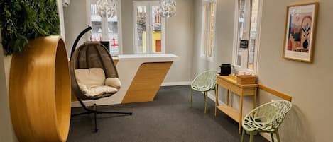 A modern interior with a hanging chair, a wooden bench, and a reception desk.