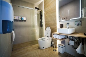 A modern bathroom with a glass-enclosed shower, a white toilet, a sink with a mirror, and a towel rack. - Futurotel Sevilla (Seville)