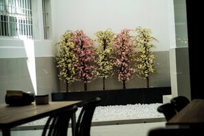 A modern interior with a seating area, a wall-mounted planter with flowering trees, and a tiled floor. - Futurotel Sevilla (Seville)