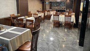 Ein Restaurant mit Marmorböden, Holzböcken und mit weißen Tischdecken bedeckten Tischen.