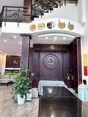 A modern lobby with a grand staircase, a reception desk, and a large potted plant. - Vuong Gia Hotel DL - by BAY LUXURY (Cam Ly - Da Lat)