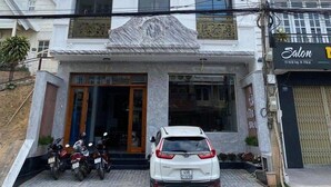 Ein Hotel namens VUONGGIA mit einer auffälligen vertikalen Beschilderung, einer modernen Fassade und einem geparkten Auto davor.