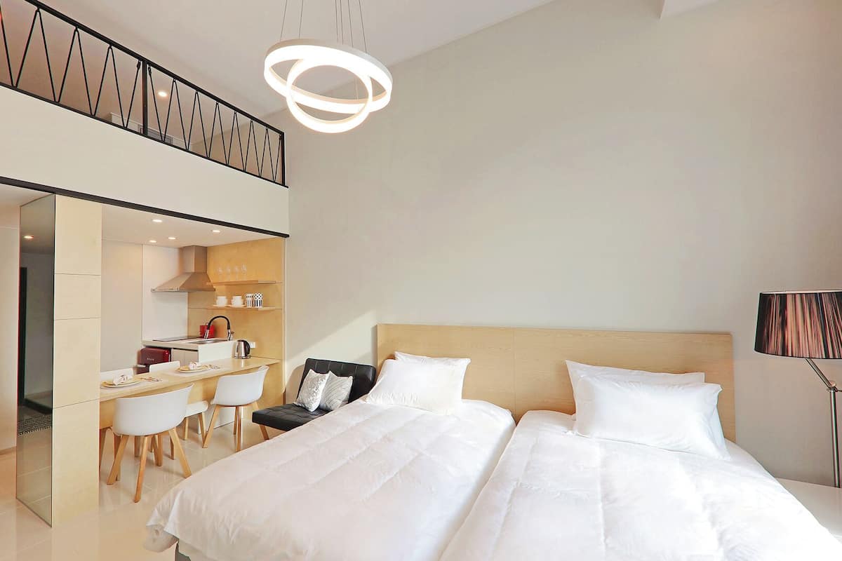 Ein modernes Hotelzimmer mit einem großen Bett, einem Schreibtisch mit Stühlen und einer Küchenzeile.