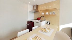 Cocina compacta con estufa moderna, lavaplatos y un refrigerador pequeño.