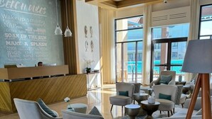 Eine moderne Lobby mit einer Rezeption, gemütlichen Sitzgelegenheiten und großen Fenstern mit Blick auf den Pool.