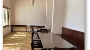Ein Konferenzraum mit langem Tisch und Stühlen, einem gemusterten Boden und einer Bank an einer Wand.