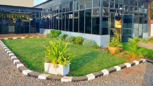 A modern building with large glass windows and a well-maintained lawn with potted plants. - Lux Suites Tsavo Sunset Apartments  (Nairobi)