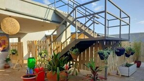A rooftop terrace with a metal staircase, potted plants, and a wooden fence. - Lux Suites Tsavo Sunset Apartments  (Nairobi)