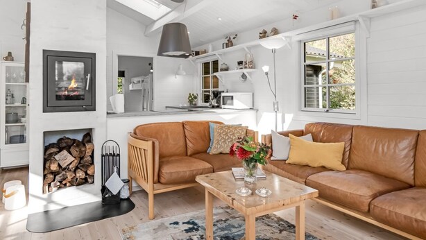 A modern living room with a brown leather sofa, a wooden coffee table, and a fireplace.