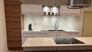 Una cocina moderna con una isla central, armarios blancos y una estufa integrada.