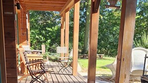 Een houten terras met een pergola, buitenmeubels en een pad van stenen.