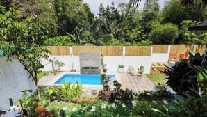 Ein Garten mit Swimmingpool, umgeben von üppigem Grün und einem Holzzaun.