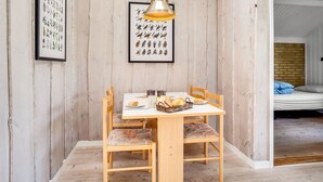 Una mesa de comedor de madera con sillas, un grabado botánico enmarcado y una ilustración de pájaro en la pared.
