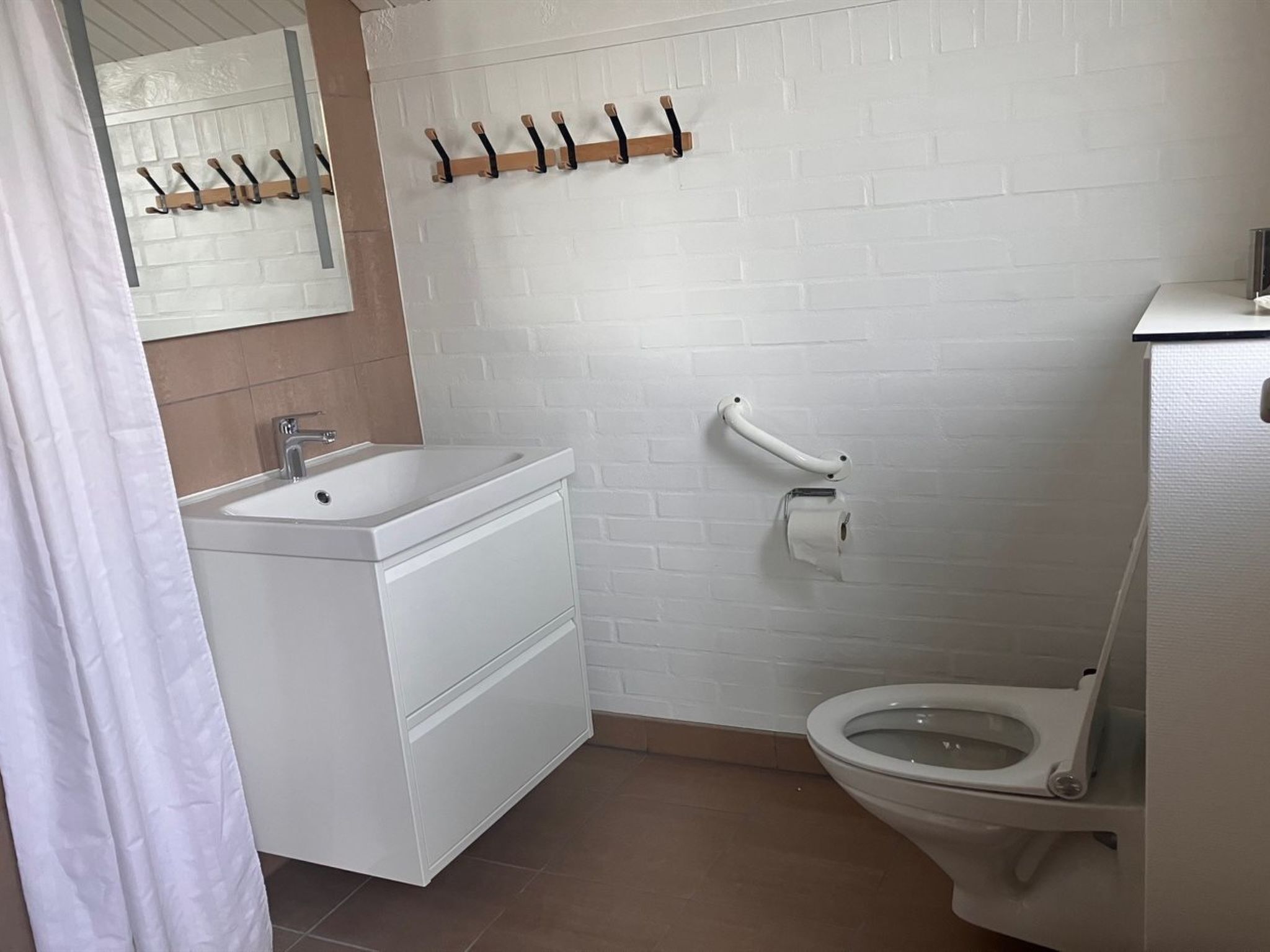 Et badeværelse med en hvid vask, toilet og håndklædestang.
