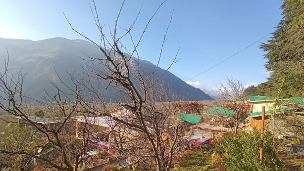 A mountainous landscape with a village featuring traditional houses with green roofs. - Mahamaya Resort (Manali)
