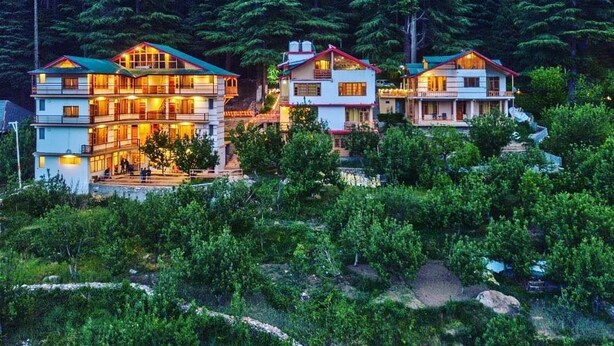 Ein mehrstöckiges Hotel mit einem zentralen Innenhof, umgeben von dichtem Wald.