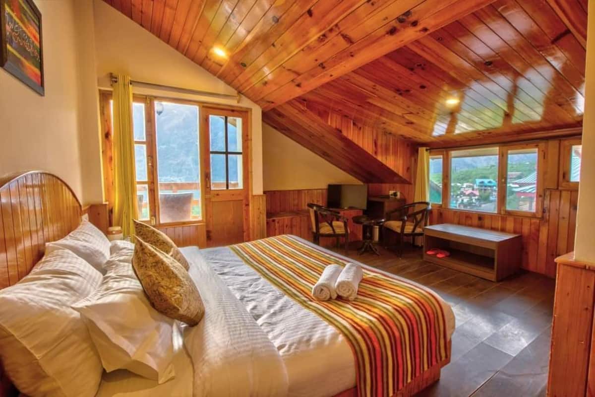 A wooden-paneled bedroom with a bed, a desk, and a bench.