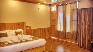 Ein Schlafzimmer mit Holzboden, einem großen Bett, einer Holzkolle und Blick ins Freie.