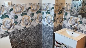 A bathroom with a toilet, sink, and shower. The walls are decorated with a floral pattern. - Mahamaya Resort (Manali)