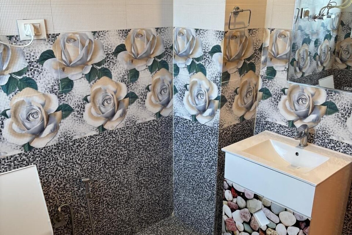 A bathroom with a toilet, sink, and shower. The walls are decorated with a floral pattern.
