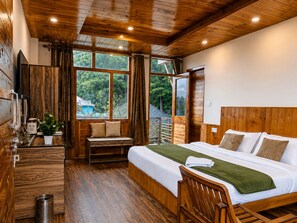 A wooden cabin with a bed, a bench, a small table with a plant, and a window overlooking greenery. - Mahamaya Resort (Manali)