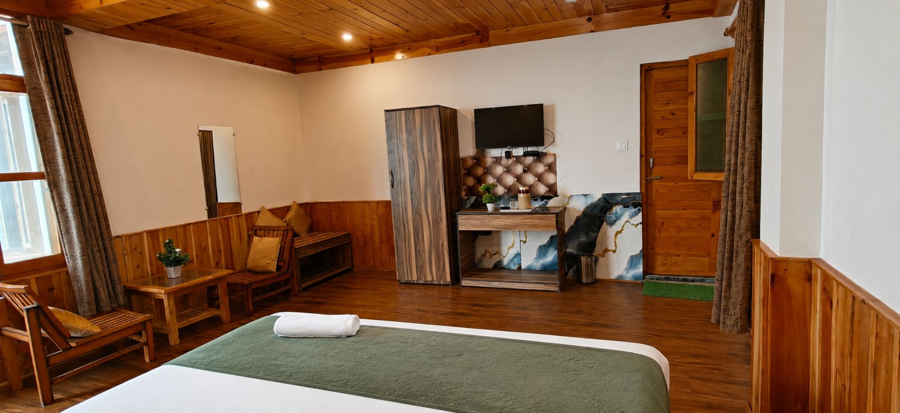 Une chambre avec un lit, des meubles en bois, une télévision et un panneau décoratif au mur.