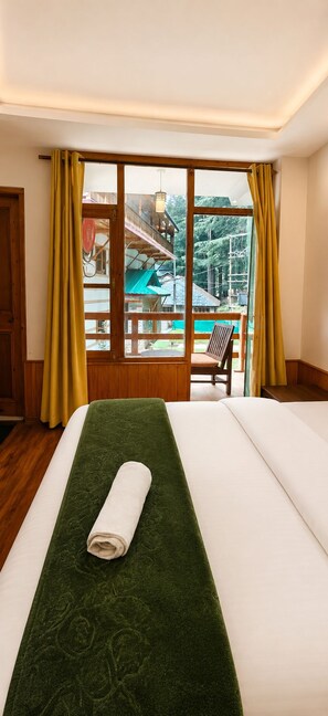 A hotel room with a bed, a view of a pool, and a chair outside. - Mahamaya Resort (Manali)