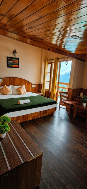 A room with a wooden bed, a small table, and a view of the outdoors. - Mahamaya Resort (Manali)