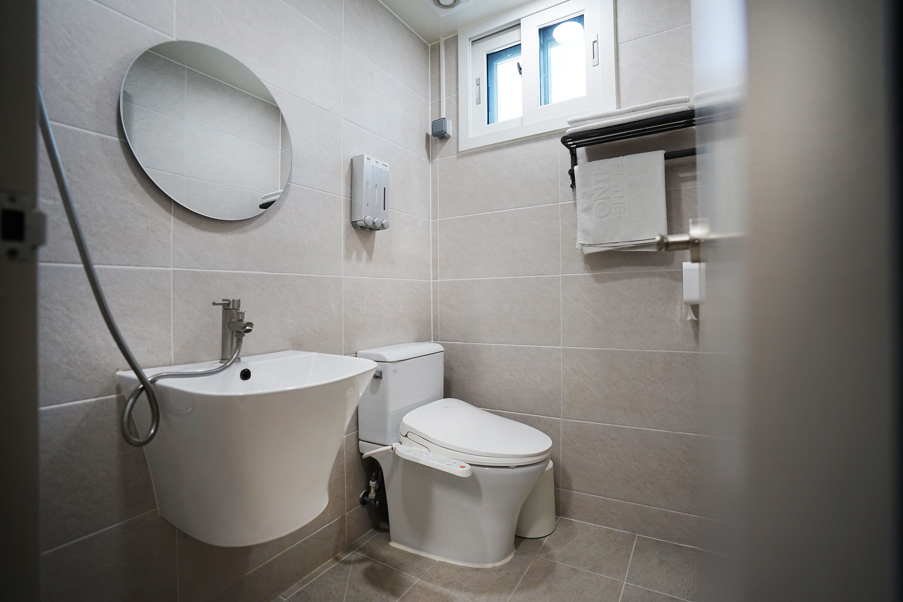 Un baño con lavamanos, inodoro y espejo.