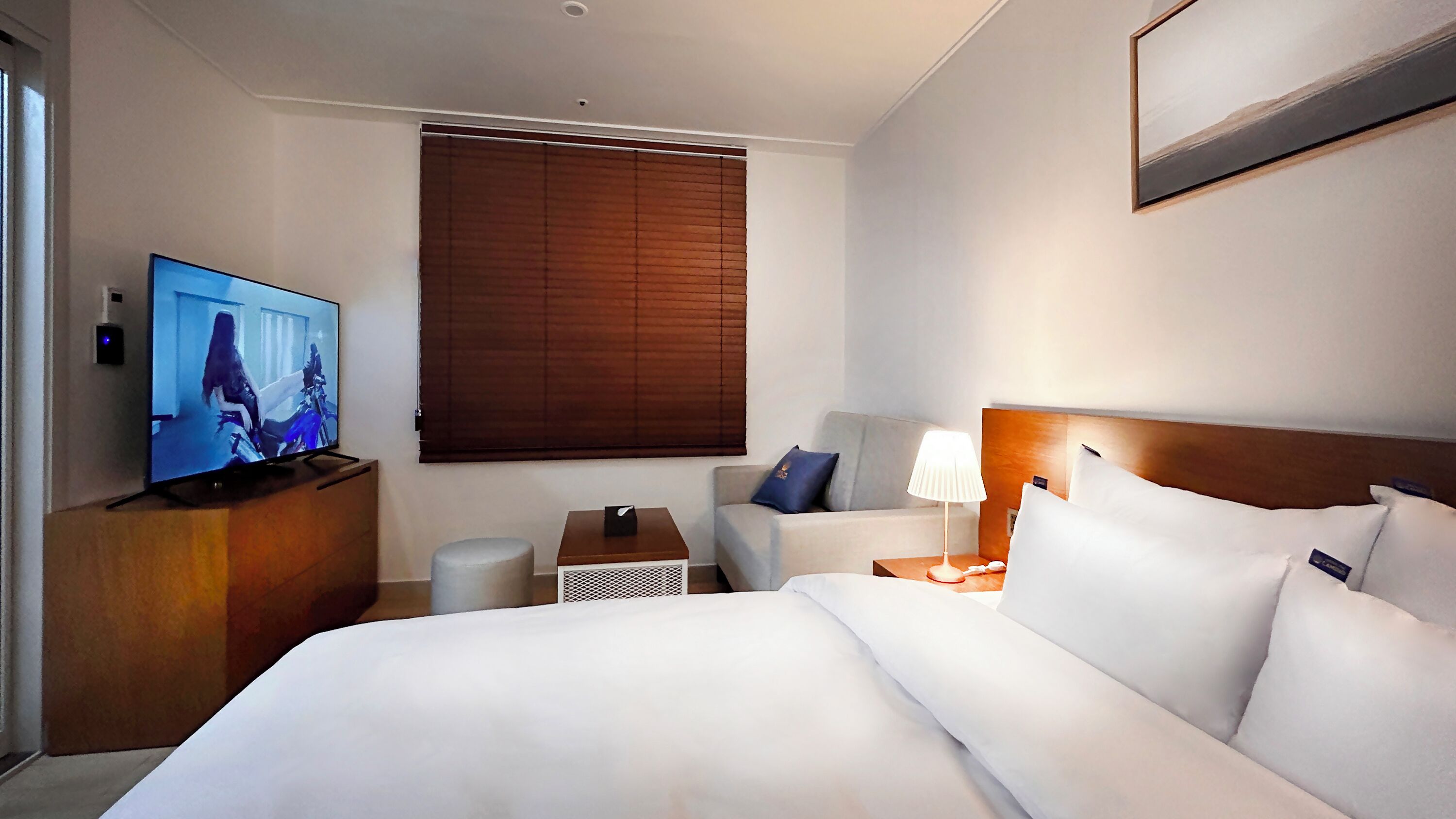 Une chambre d’hôtel équipée d’un lit, d’une télévision, d’un bureau, d’une chaise et d’une table de chevet.