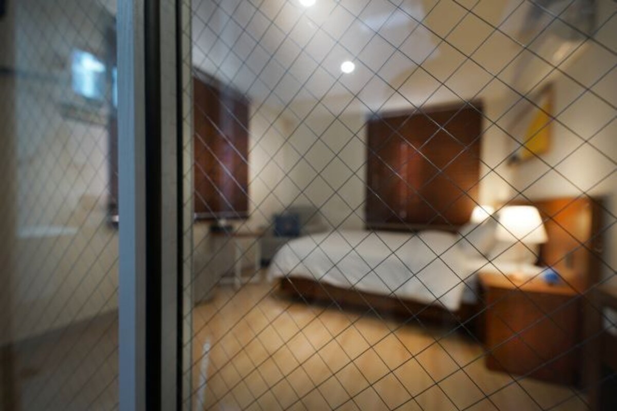 Een hotelkamer met een bed, nachtkastje en een lamp.